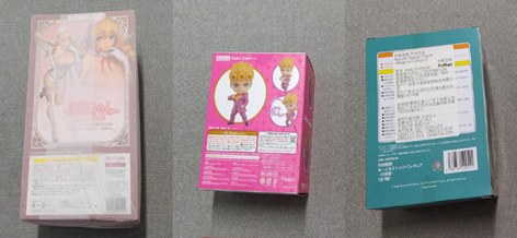 Three sealed figure boxes photographed closed, with their shrink wrap still on