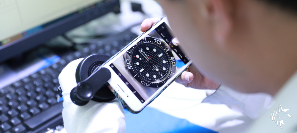 A technician examining a wristwatch through a loupe at an identification centre